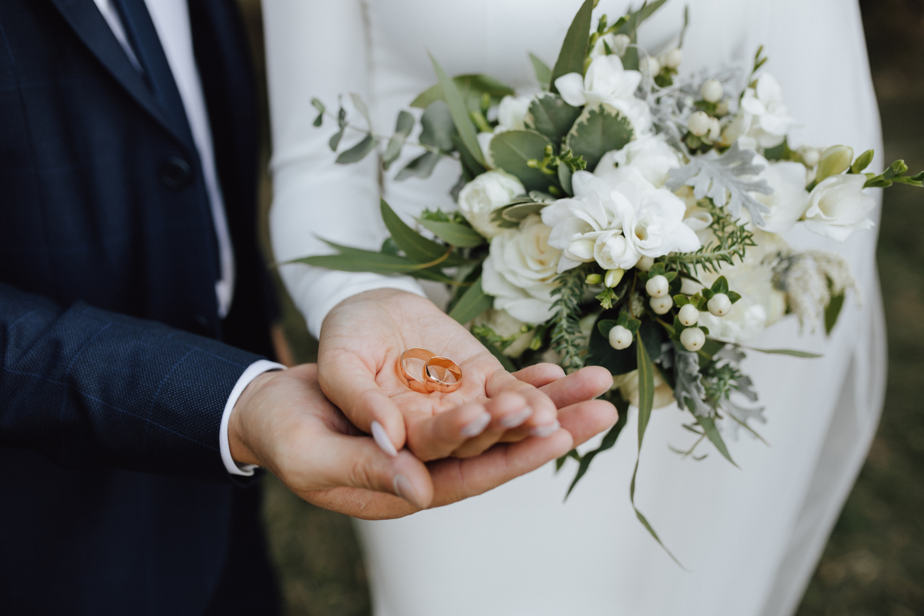 wedding-bands-in-the-hands-of-bride-and-groom-and-with-beautiful-wedding-bouquet-made-of-greenery-and-white-flowers.jpg
